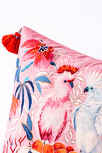 Square pink velvet cushion cover featuring illustrated cockatoos, floral motifs and red tassel corners