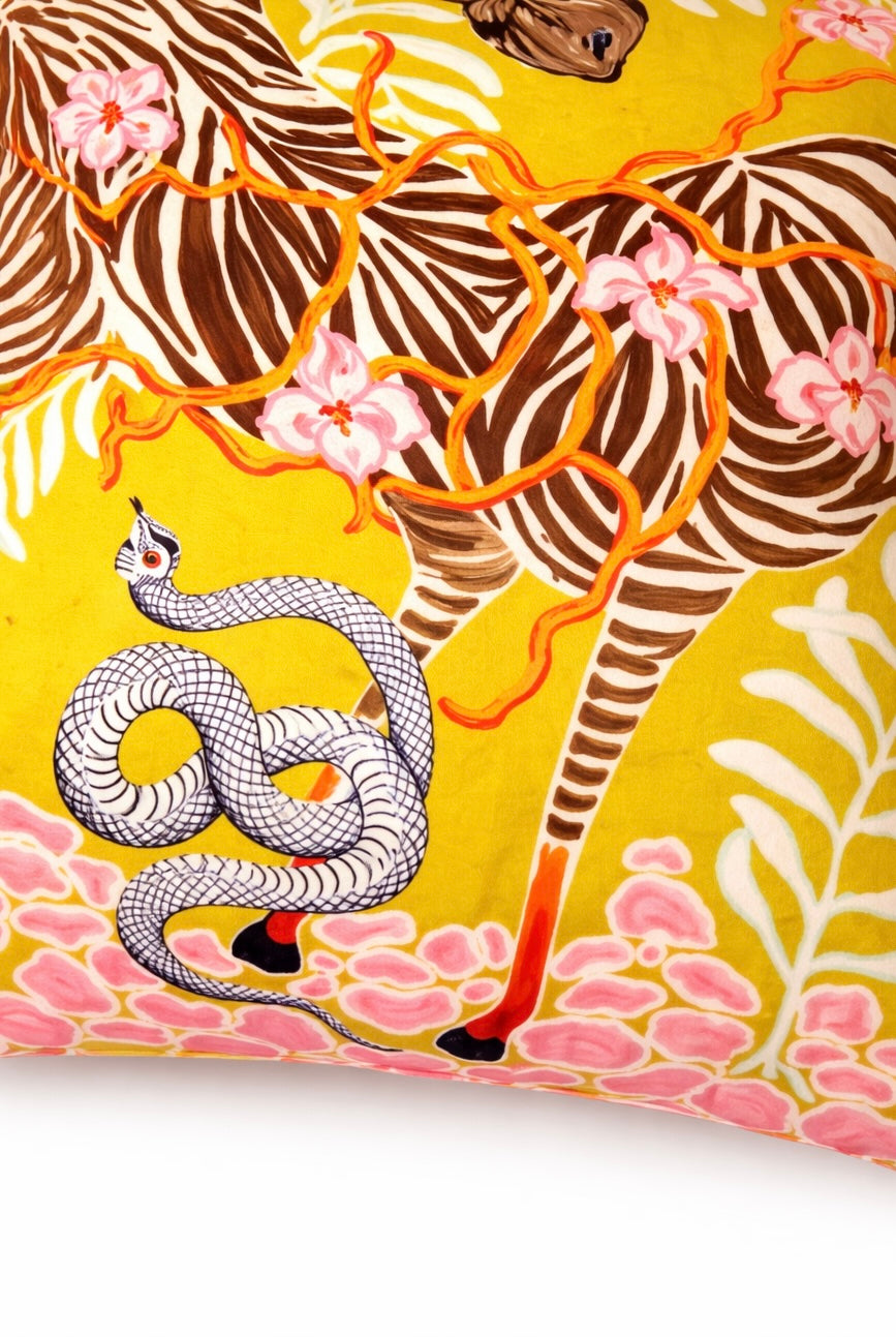 Yellow velvet cushion cover with illustrated zebra, floral branches, snake motif and pink corner tassels