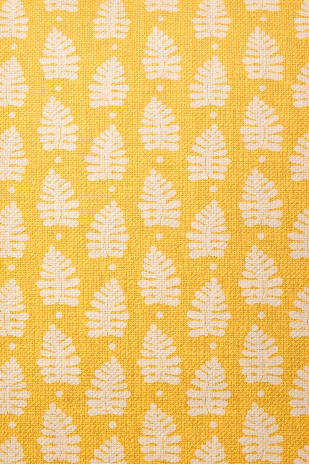 Yellow square cushion with a repeating white leaf botanical motif