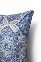 Blue and ivory square cushion with a repeating ornamental medallion pattern