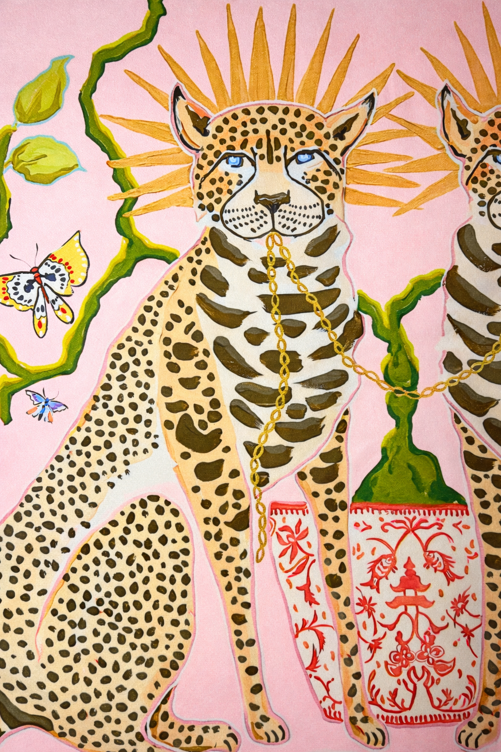 Pink velvet cushion cover with two illustrated cheetahs, sunburst halos, birds, floral branches and brown tassel corners