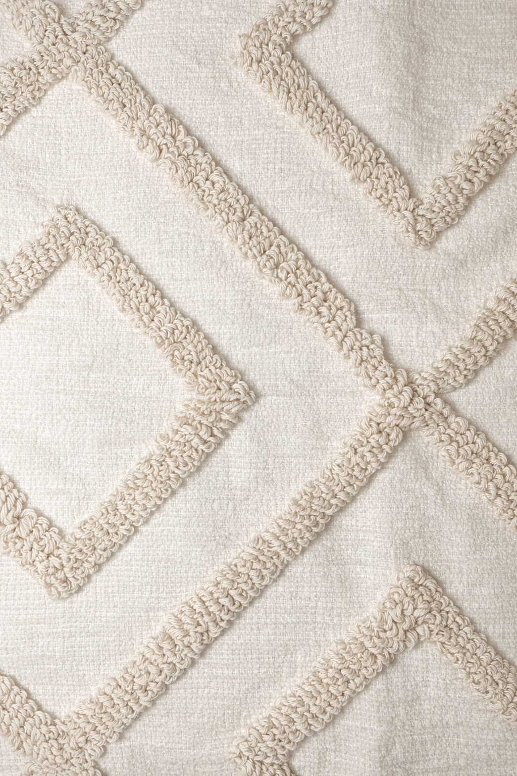 Beige square cushion with raised diamond tufted pattern and tassel corners