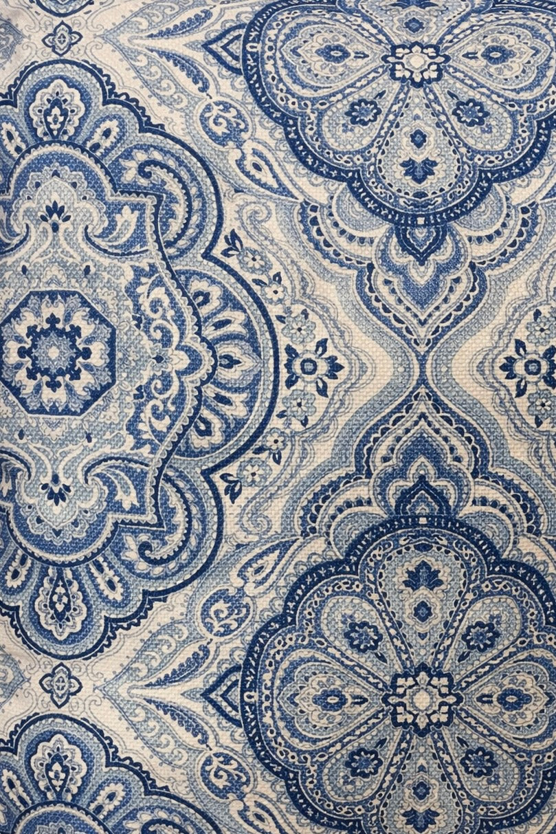 Blue and ivory square cushion with a repeating ornamental medallion pattern