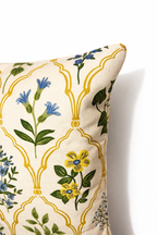 Cream square cushion with blue floral motifs and repeating arched lattice pattern