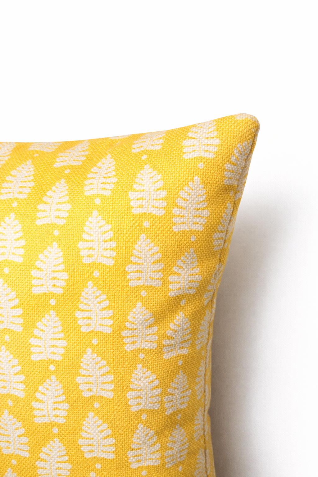 Yellow square cushion with a repeating white leaf botanical motif