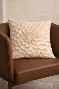 Beige velvet square cushion cover with layered floral appliqué texture and sculpted petal detailing.