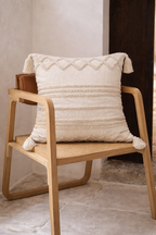 Beige square cushion with tufted geometric patterns and tassel corners