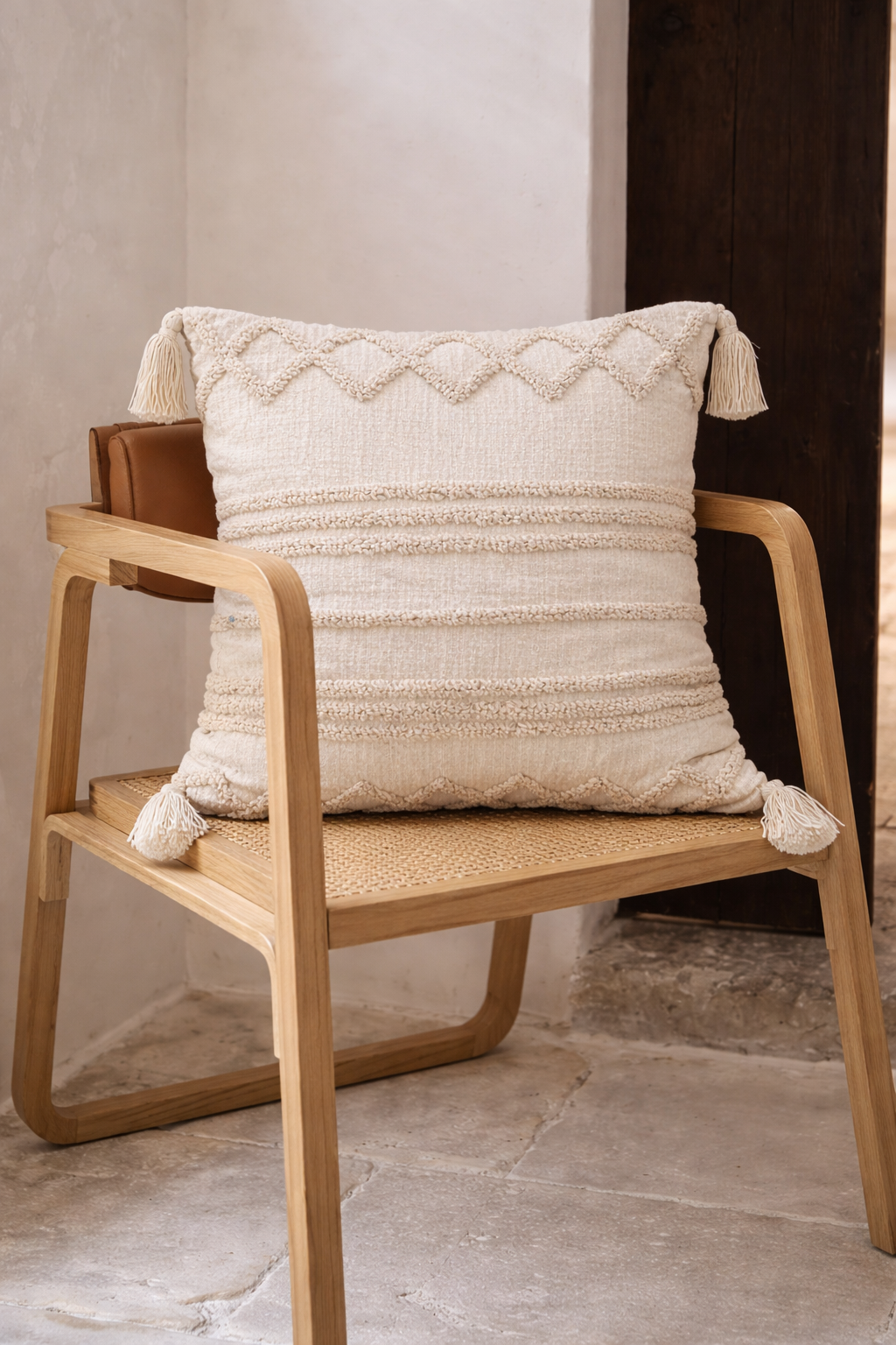 Beige square cushion with tufted geometric patterns and tassel corners