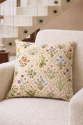 Cream square cushion with multicolour botanical flowers in a repeating trellis lattice pattern